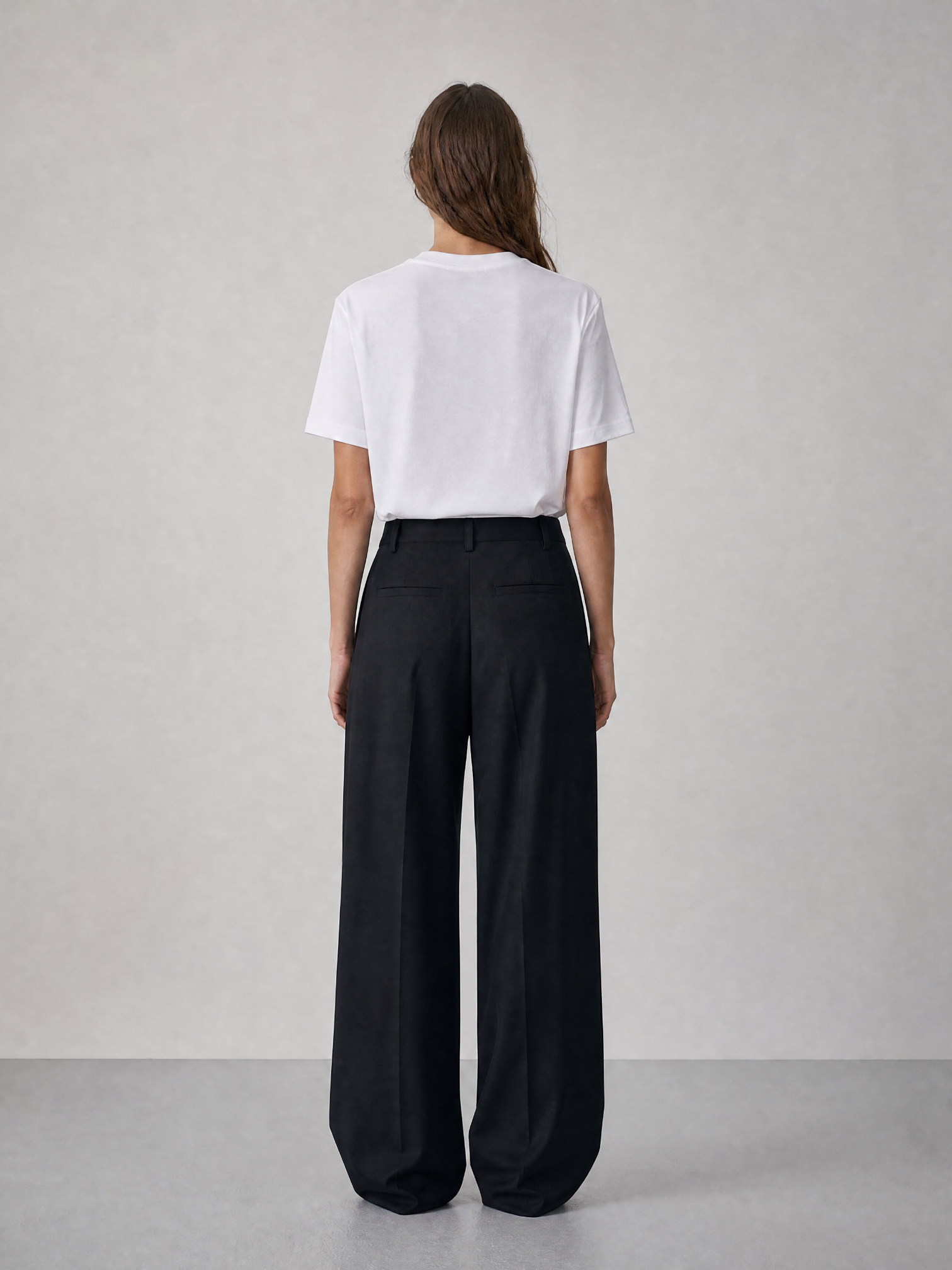 Person wearing a white t-shirt and black wide-leg pants against a plain background
