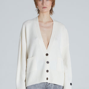 Woman wearing a Luxury cashmere cardigan in Cream color, a deep V-neck cardigan with a front button-up closure, front pockets, and ribbed trims. 