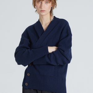 Woman wearing Luxury cashmere cardigan in Navy. Buttoned, timeless, versatile, and sustainable produced. She also wears black pants. 
