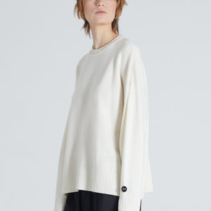Woman wearing white cashmere crewneck. She is also wearing black trousers. 