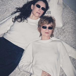 Two women, wearing matching cashmere crewnecks.