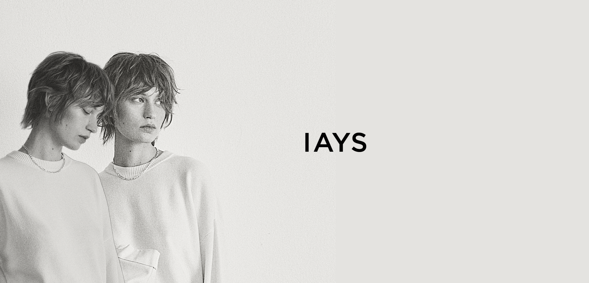 Two people wearing white sweaters with 'IAYS' logo on a light gray background